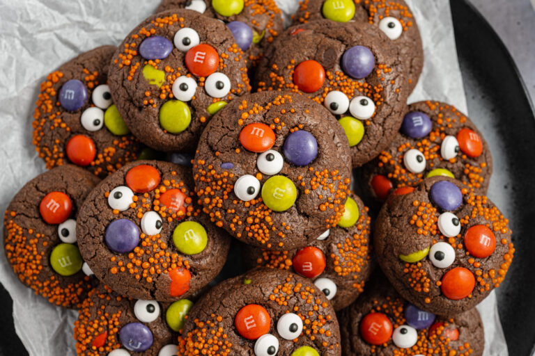 Halloween Monster Cookies Piled on a plate that's lined with parchment paper.