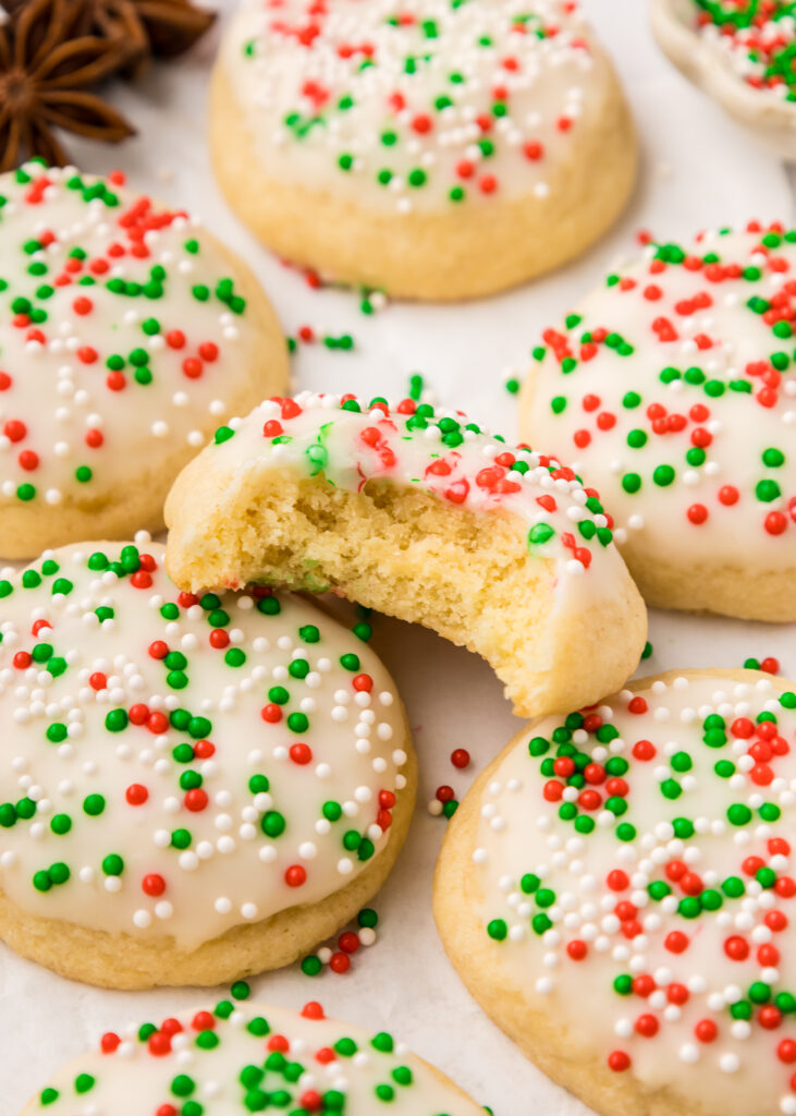 Italian Christmas Cookies laid out on a table, and one has a bite taken out of it.
