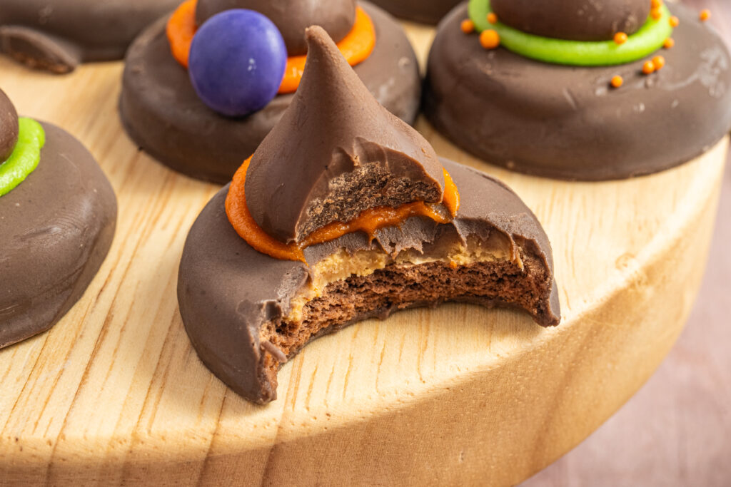 Peanut Butter Witch Hat Cookie with a bite taken out of it on a small wood display.