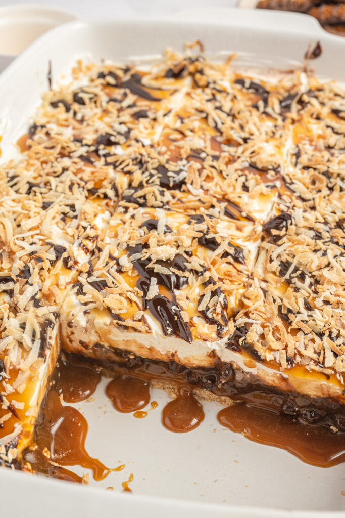 Samoa Lasagna in a baking dish with a couple of slices missing.