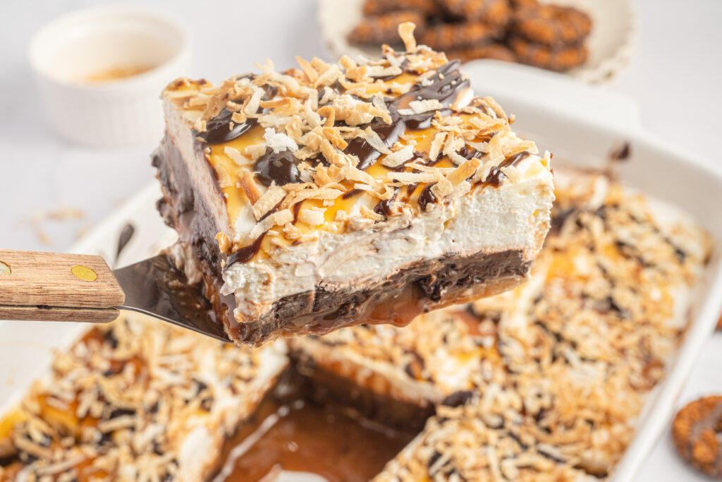 A slice of Samoa Lasagna being held above the rest of the dessert.