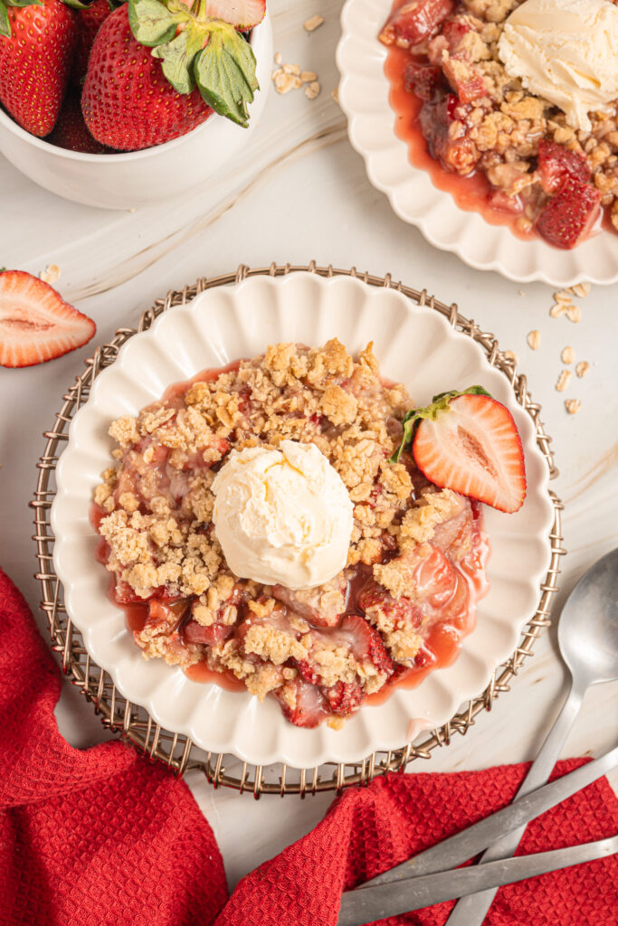 Strawberry Rhubarb Crisp on a small plate with vanilla ice cream on top.