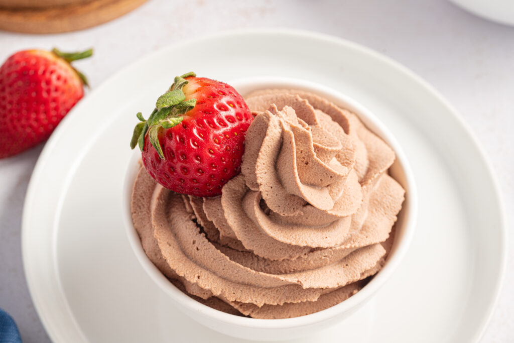 Chocolate Whipped Cream swirled into a small bowl with a strawberry on top.