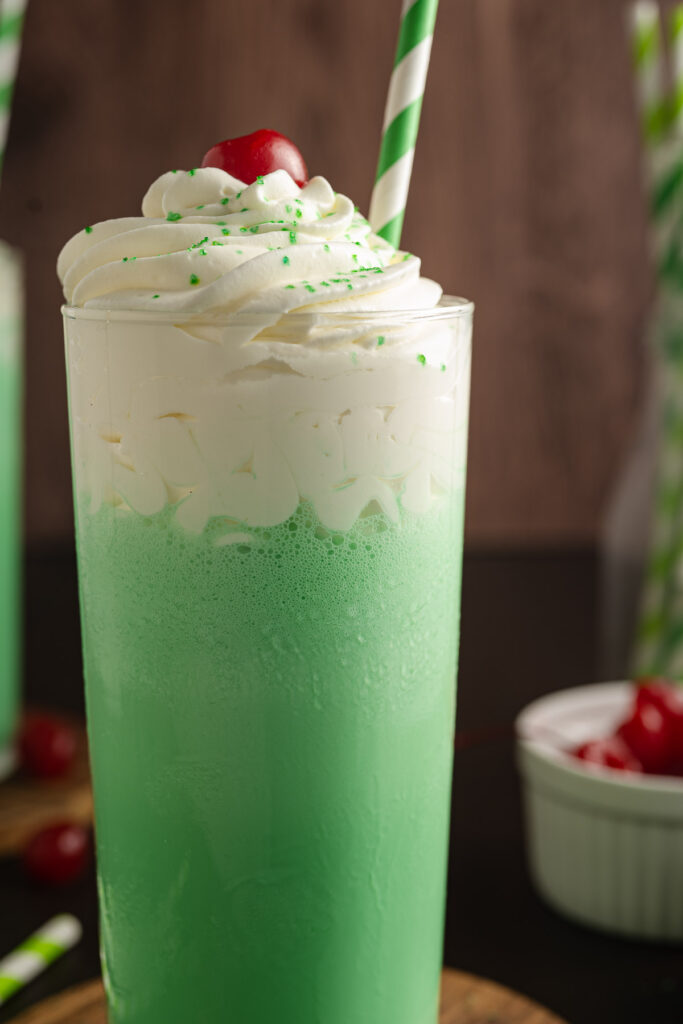 Shamrock Shake on a table with cherries in the background.