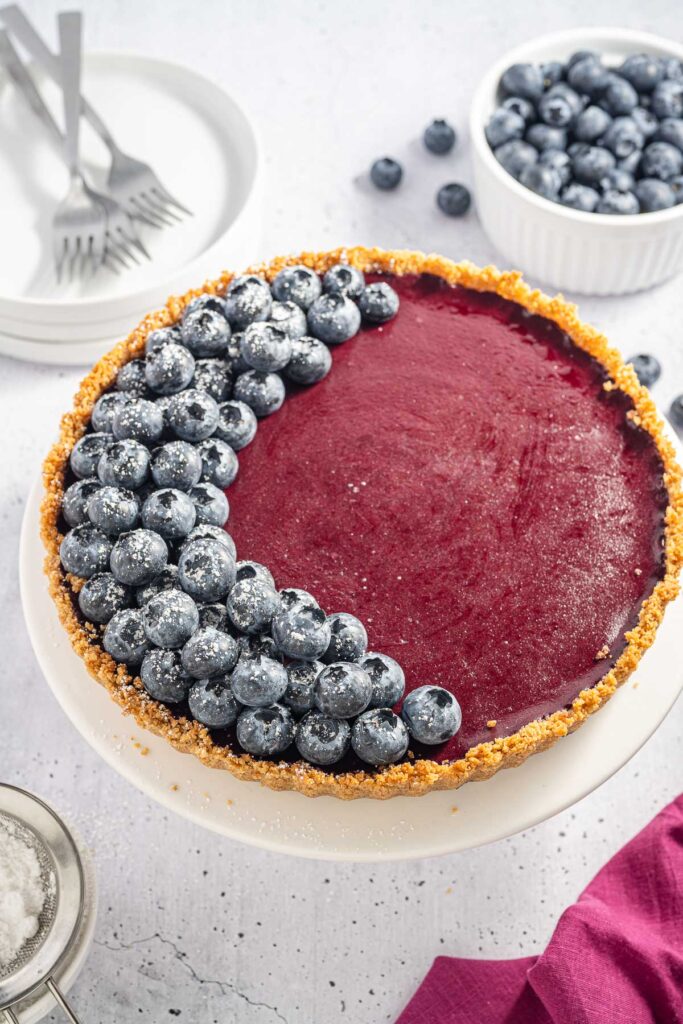 Blueberry Curd Tart on a table with fresh blueberries on top.