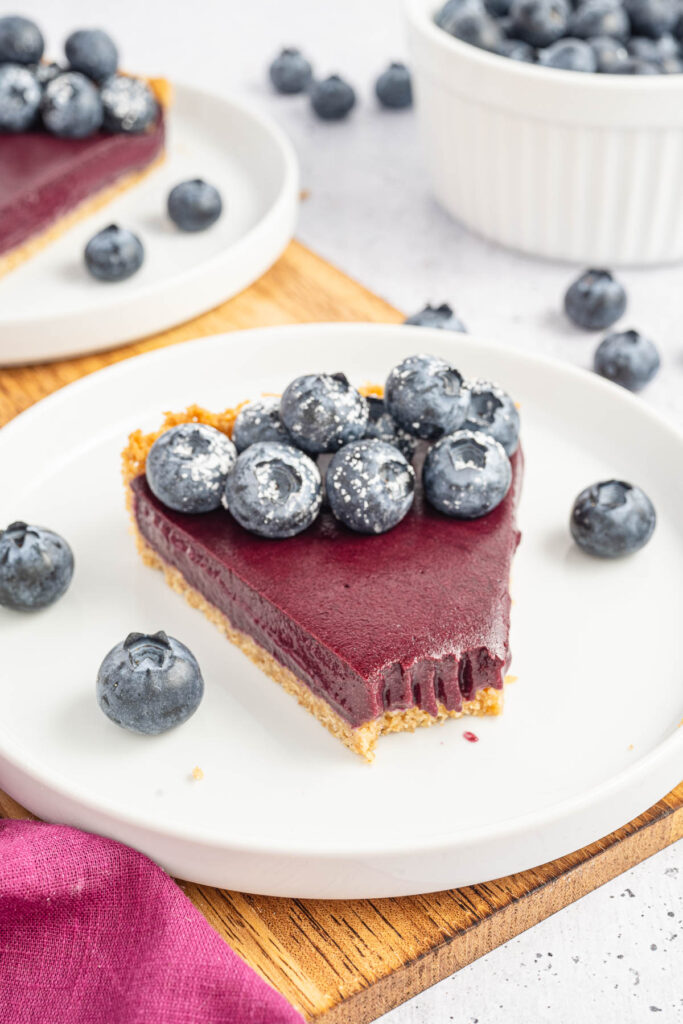 A slice of Blueberry Curd Tart with a bite taken out of it.
