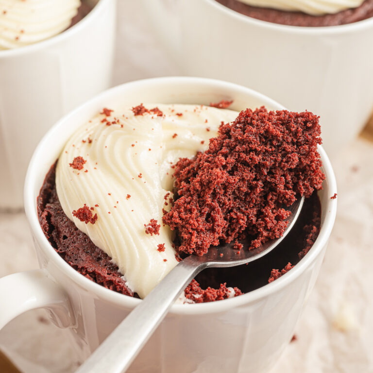 Red Velvet Mug Cake with a spoonful resting on top of the mug.
