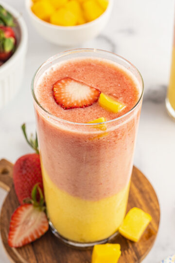 Strawberry Mango Smoothie served on a wooden coaster on a table.