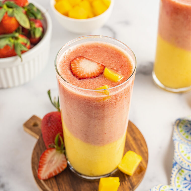Strawberry Mango Smoothie served on a wooden coaster on a table.