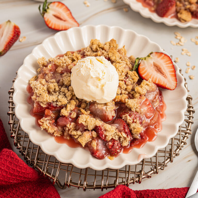 Strawberry Rhubarb Crisp on a small plate with a scoop of vanilla ice cream on top.