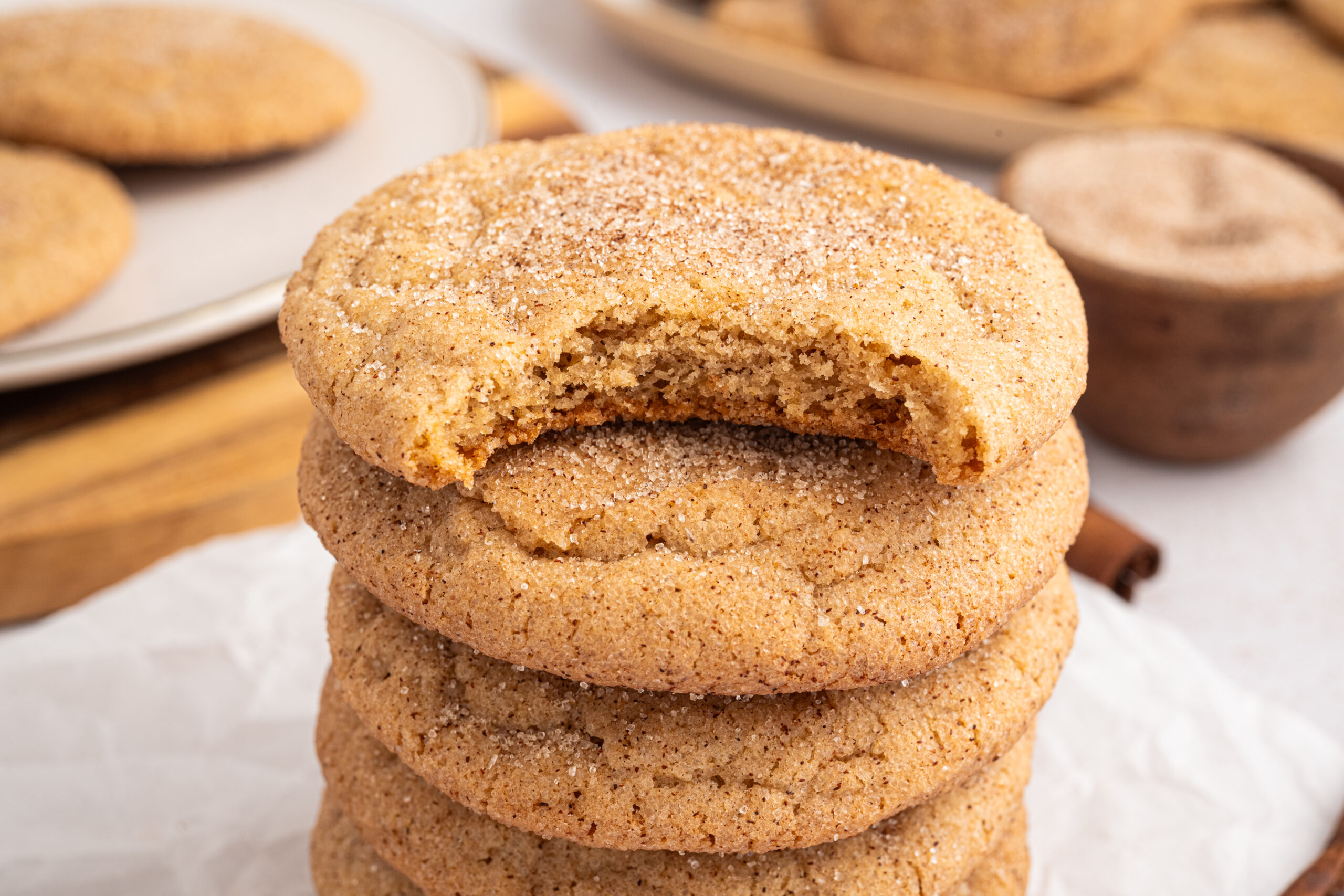 A stack of maple snickerdoodles and the top cookie has a bite taken out.