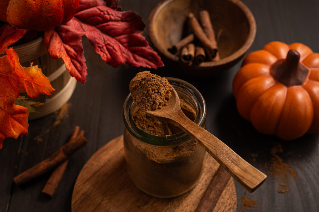 Homemade Pumpkin Pie Spice in a jar with a spoon on top.