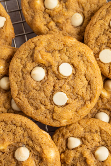 White Chocolate Chip Pumpkin Cookies piled on a cooling rack.