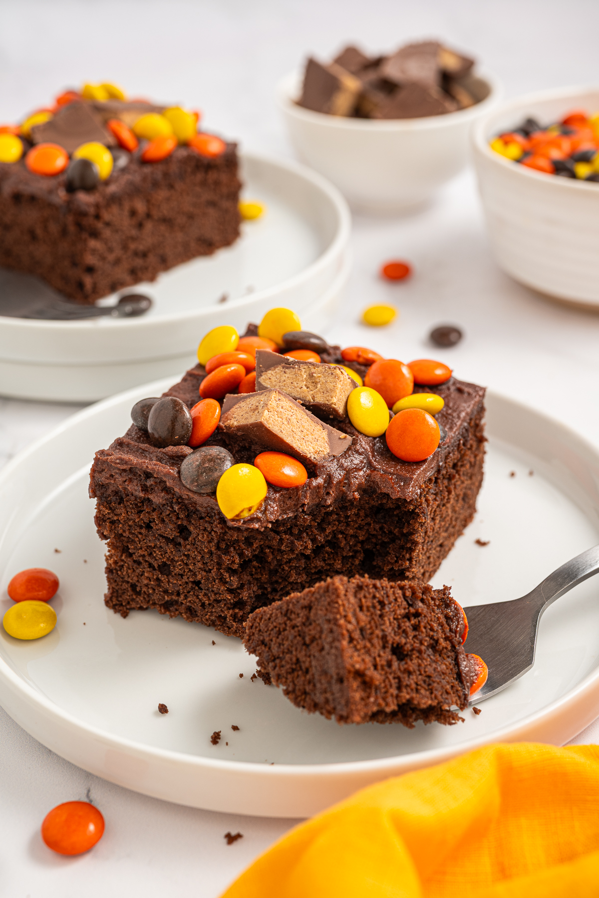 A slice of Chocolate Peanut Butter Sheet Cake on a small white plate with a bite taken out of it.